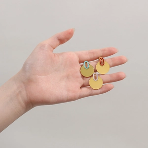 Detailed shot of three gold stainless steel round earrings with colorful enamel charms