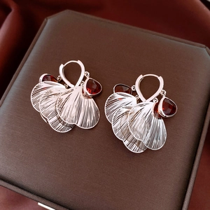 Macro view of rose gold hollow fan earrings with deep red teardrop-shaped gemstones