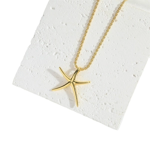 Minimalist gold starfish pendant necklace on a textured stone display background