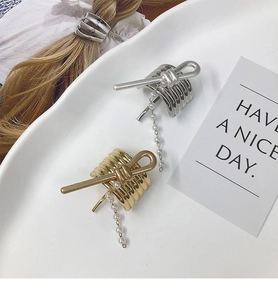 Close-up of gold and silver metal hair hooks with elegant pearl tassel on a white plate