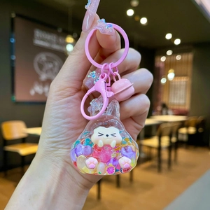 Detail of pink resin bell keychain with white cartoon figure and glitter sand