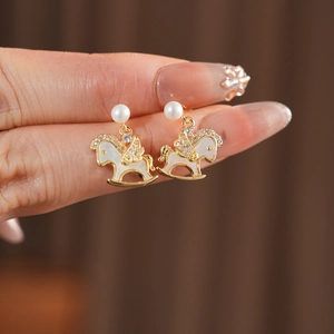 Macro view of 14k gold plated pony earrings with zircons and pearls held by hand