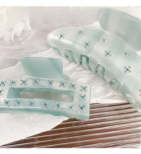 Detailed view of light blue acetate hair claws with sparkling inlaid rhinestone flowers