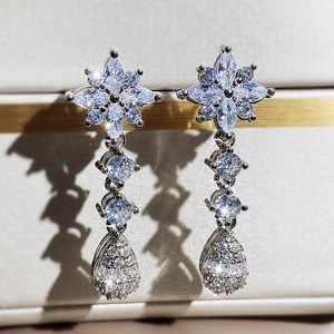 Dettaglio macro di orecchini floreali in argento con cristalli di zircone a goccia lucenti
