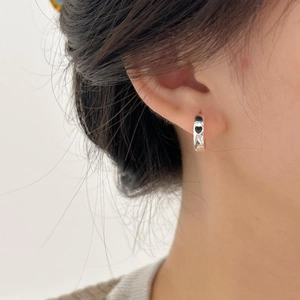 Close-up of a silver heart hoop earring with black enamel on model's ear