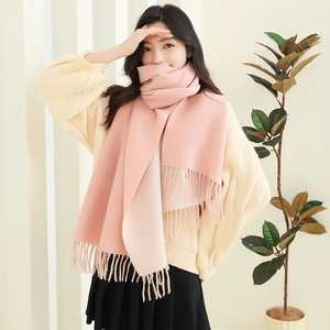 Detailed view of pink knitted scarf with soft tassels for winter warmth and style