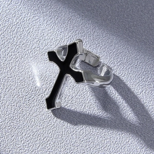 Detailed view of gothic silver cross ring with black enamel on purple textured background