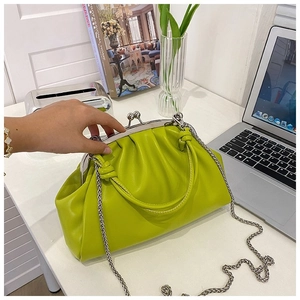 Détail du sac plissé vert vif avec fermoir argenté et bandoulière en chaîne métal