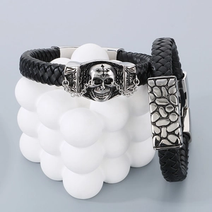 Detail of black braided leather bracelets with stainless steel skull and textured charms