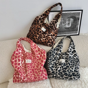Three leopard print canvas tote bags in brown, pink and grey on a cozy beige sofa