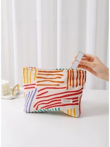 Striped floral corduroy cosmetic bag for makeup storage shown in use on a white surface