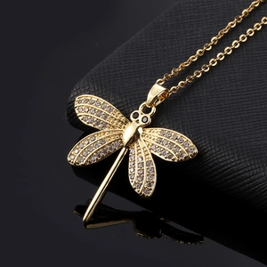 Macro shot of gold-plated dragonfly pendant with cubic zirconia and delicate chain