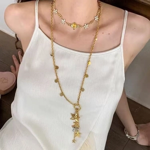 Close-up of double-layered gold necklace with floral charms and star fringe pendants