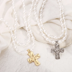 Detail of layered freshwater pearl necklaces with gold and silver cross pendants