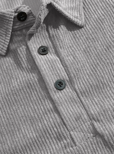 Detail shot of grey corduroy polo shirt collar with three black functional buttons