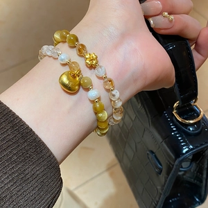Détail de bracelets en perles d'œil de tigre avec breloques dorées en forme de cœur et fleur