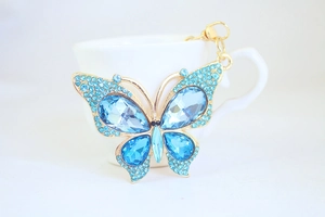 Macro detail of gold butterfly keychain with blue faceted crystals and rhinestones