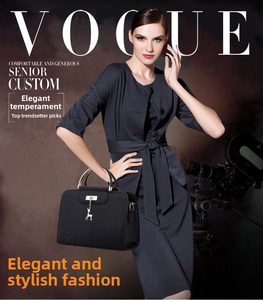 Detail of black embossed handbag with gold deer charm and round metal handle shown with model
