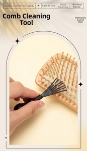 Macro view of a black cleaning claw tool removing hair from a wooden massage hairbrush