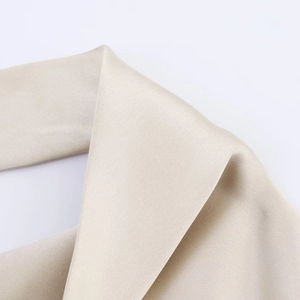 Détail macro du tissu satiné montrant la texture sergé et l'éclat soyeux du vêtement