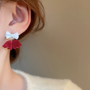 Close-up of model wearing velvet red bell earrings with a white bow knot detail