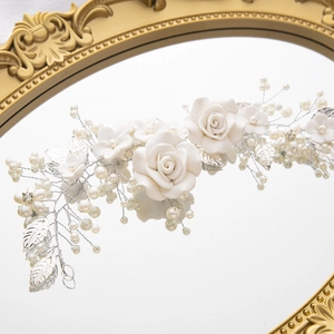 Detailed view of silver bridal vine headband with white flowers and pearls on a vintage mirror
