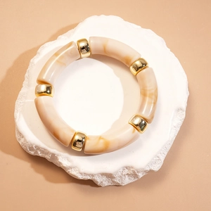 Détail de segments en acrylique marbré et billes dorées sur un bracelet géométrique