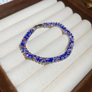 Gros plan détaillé d'un bracelet à maillons carrés en zircon bleu fleuri dans son écrin