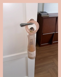 Close-up of pink wine opener with rhinestone bottle charm hanging on white door handle