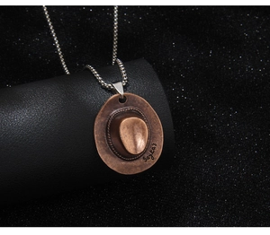 Detailansicht eines Vintage Cowboyhut Anhängers aus Bronze mit Sayka's Gravur auf schwarzem Halter