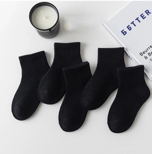 Five pairs of black mid-calf cotton socks arranged with a minimalist lifestyle aesthetic