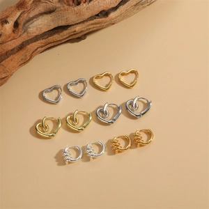 Set of vintage heart-shaped hoop earrings in gold and silver finish on neutral background