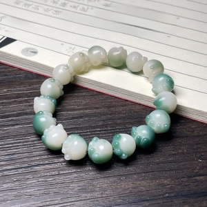 Macro shot of cat paw shaped beads bracelet with translucent green and white gradient finish