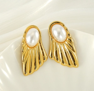 Detail of fan-shaped gold earrings with oval pearls on elegant white tray background