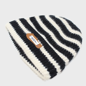 Detailed view of striped knit beanie showing the texture and Ader letter patch logo