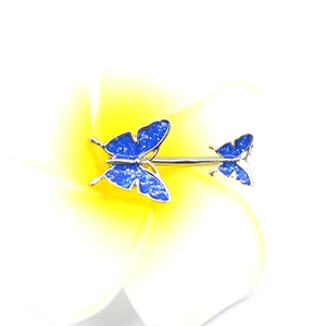 Macro shot of blue glitter butterfly belly ring on petals, detail of steel piercing jewelry