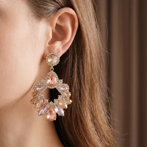Luxury geometric hollow drop tassel earrings with sparkling crystals worn by a model