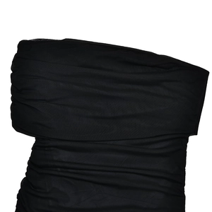 Détail de la maille à épaules dénudées et du tissu plissé sur une robe noire moulante