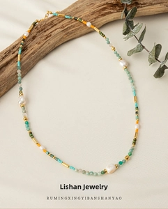 Detail of colorful beaded necklace with freshwater pearls and green stone beads