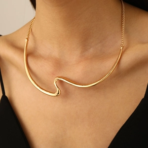 Close-up of golden geometric wavy necklace on model's neck with minimalist metal texture