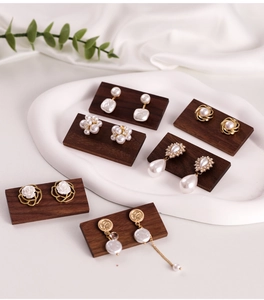 Retro pearl and gold earrings displayed on a dark walnut wood jewelry stand