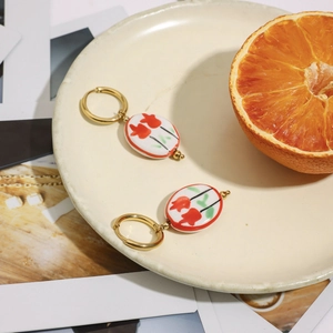 Dettaglio di orecchini a cerchio in oro 18K con ciondolo a tulipano in ceramica