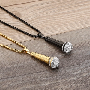 Detail of gold and black microphone pendants with crystal inlay on a wooden background
