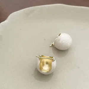 Détail de créoles de luxe en émail crème avec texture brossée et accents dorés