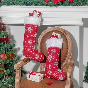 Red Christmas stockings with white snowflake embroidery and plush trim on a wooden chair