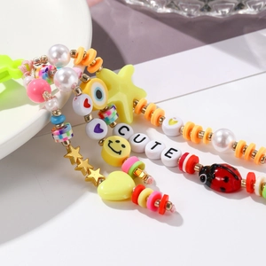 Gros plan sur un porte-clés en perles colorées avec lettrage CUTE, smiley et coccinelle