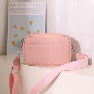 Detail view of pink lychee leather crossbody bag with wide nylon strap and silver hardware