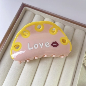 Detail of pink and yellow acetate hair claw clip with LOVE letters and lip pattern