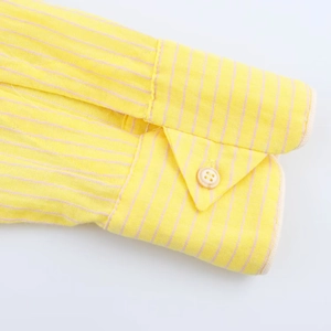 Gros plan du poignet d'une chemise rayée jaune et rose en coton avec bouton en résine