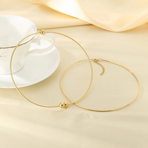 Detail of twisted gold wire chokers with beads displayed on soft beige silk fabric